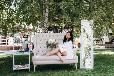 Siyah saçlı gelin evlenmeye hazırlanıyor. Bahçedeki bir yatak odasında.