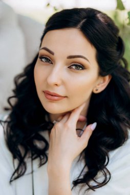 Siyah saçlı gelin evlenmeye hazırlanıyor. Bahçedeki bir yatak odasında.