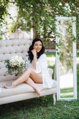 Siyah saçlı gelin evlenmeye hazırlanıyor. Bahçedeki bir yatak odasında.