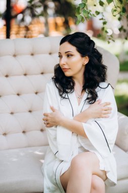 Siyah saçlı gelin evlenmeye hazırlanıyor. Bahçedeki bir yatak odasında.