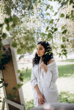 Siyah saçlı gelin evlenmeye hazırlanıyor. Bahçedeki bir yatak odasında.