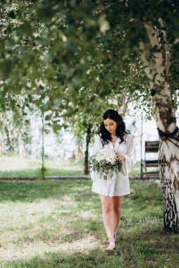 Siyah saçlı gelin evlenmeye hazırlanıyor. Bahçedeki bir yatak odasında.