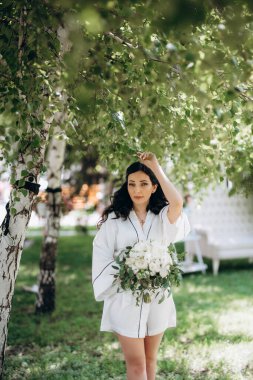 Siyah saçlı gelin evlenmeye hazırlanıyor. Bahçedeki bir yatak odasında.