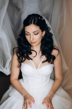 portrait of a bride in the morning before the wedding with putting on a white dress