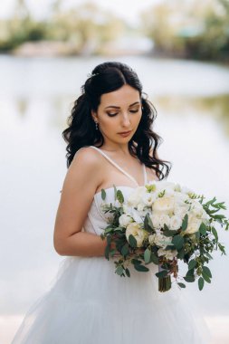 Gelin, sarı bir günbatımının arka planında nehir kıyısındaki bir iskelede