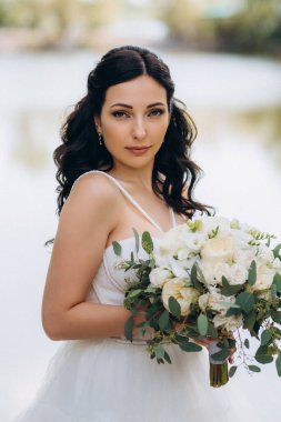 Gelin, sarı bir günbatımının arka planında nehir kıyısındaki bir iskelede