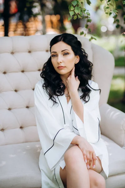 Siyah saçlı gelin evlenmeye hazırlanıyor. Bahçedeki bir yatak odasında.