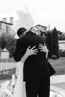 Gelin ve damadın bir restoranda düğün töreni. Beyaz kanatların ve mavi bir havuzun önünde.