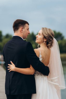 Genç çift, gelin ve damat, nehir kıyısında yürüyorlar.