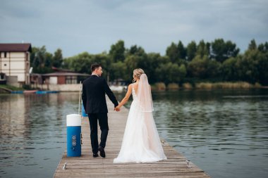 Genç çift, gelin ve damat, nehir kıyısında yürüyorlar.