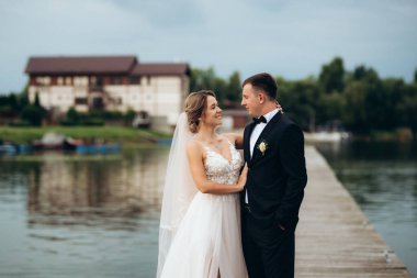 Genç çift, gelin ve damat, nehir kıyısında yürüyorlar.