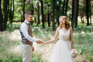 Gelin ve damat parklarda yürüyorlar patikalar boyunca ve ışık huzmeleri içinde