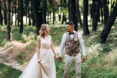 Gelin ve damat parklarda yürüyorlar patikalar boyunca ve ışık huzmeleri içinde