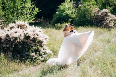 Gelin ve damat parklarda yürüyorlar patikalar boyunca ve ışık huzmeleri içinde