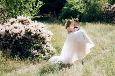 Gelin ve damat parklarda yürüyorlar patikalar boyunca ve ışık huzmeleri içinde