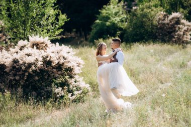 Gelin ve damat parklarda yürüyorlar patikalar boyunca ve ışık huzmeleri içinde