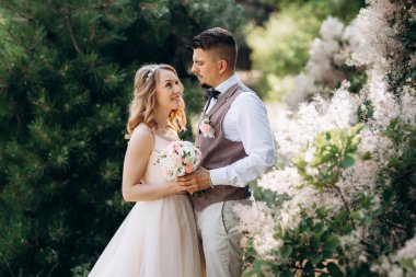 Gelin ve damat parklarda yürüyorlar patikalar boyunca ve ışık huzmeleri içinde