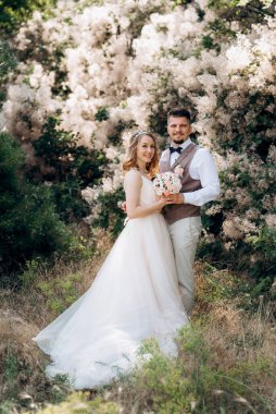 Gelin ve damat parklarda yürüyorlar patikalar boyunca ve ışık huzmeleri içinde