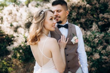 Gelin ve damat parklarda yürüyorlar patikalar boyunca ve ışık huzmeleri içinde