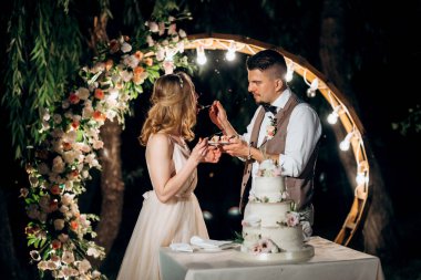 newlyweds happily cut, laugh and taste the wedding cake