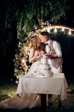 newlyweds happily cut, laugh and taste the wedding cake