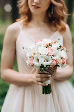 Yeşil bir bahar ormanında açık mercan elbiseli sarışın gelin.