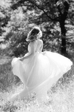 Yeşil bir bahar ormanında açık mercan elbiseli sarışın gelin.