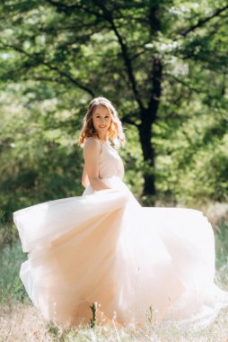 Yeşil bir bahar ormanında açık mercan elbiseli sarışın gelin.