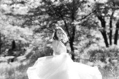 Yeşil bir bahar ormanında açık mercan elbiseli sarışın gelin.