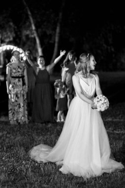 bride in a white dress throws a wedding bouquet to her unmarried girlfriends