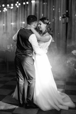 Gelin ve damadın ilk düğün dansı gün batımında restoranın içinde.