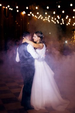 Gelin ve damadın ilk düğün dansı gün batımında restoranın içinde.