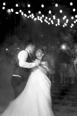 Gelin ve damadın ilk düğün dansı gün batımında restoranın içinde.