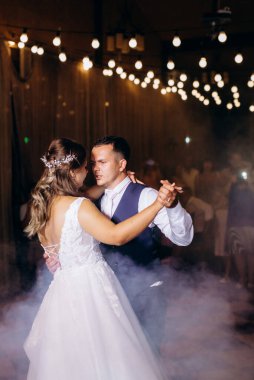 Gelin ve damadın ilk düğün dansı gün batımında restoranın içinde.