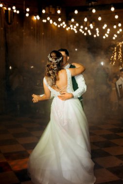 Gelin ve damadın ilk düğün dansı gün batımında restoranın içinde.