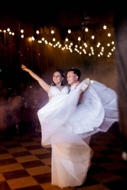 Gelin ve damadın ilk düğün dansı gün batımında restoranın içinde.