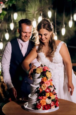 newlyweds happily cut, laugh and taste the wedding cake