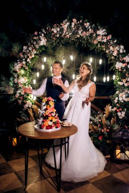 newlyweds happily cut, laugh and taste the wedding cake