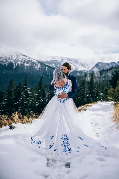 Novio en un traje azul y novia en blanco en las montañas Carpath —  Fotos de Stock