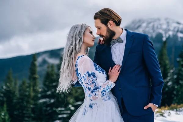 Ženich v modrém obleku a nevěsta v bílém, v horách Carpath — Stock fotografie