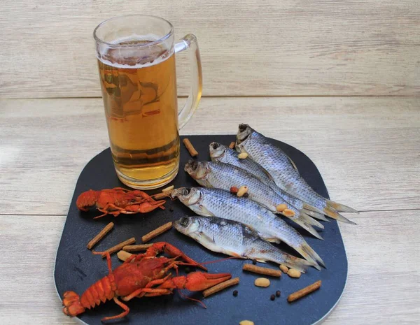 Kapatın. Bardakta soğuk bira ve karanlık bir arka planda ahşap bir masada atıştırmalıklar. Kurutulmuş balık ve fındık. Yerel bira fabrikasında fast food, pub. Oktoberfest. Hayat sakin, kırsal..