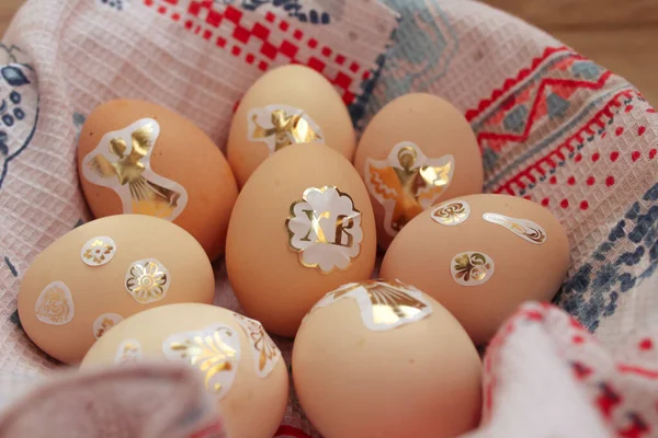 Paskalya çıkartmalarıyla süslenmiş tavuk yumurtaları havluyla kaplı bir sepetin içinde yatıyor.