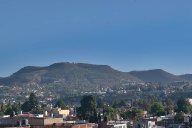 Birden fazla ev, dağ ve mavi gökyüzü.