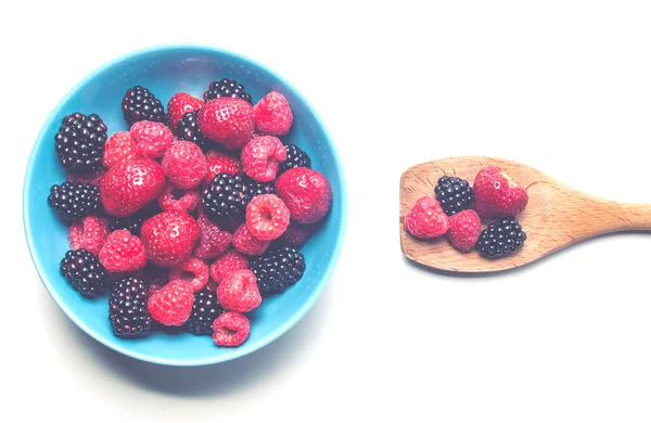 Различные ягоды в миске и деревянной ложке — стоковое фото