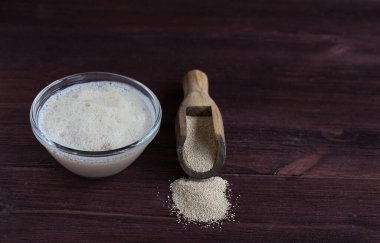 Tahta kaşıkta kuru maya ve mayalı bir bardak.