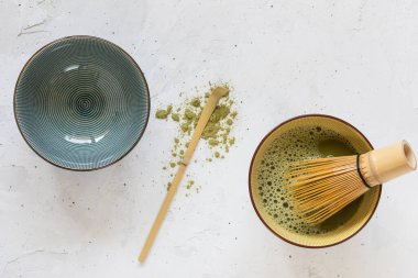 Yeşil çay bir kasede çırpılmış, boş bir kase ve aralarında dağınık bir çay tozu olan bir kaşık.