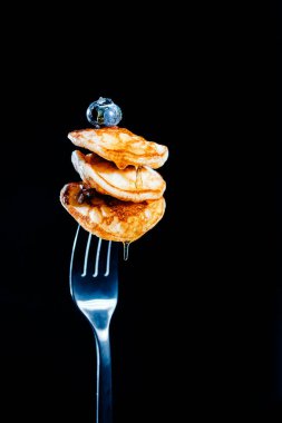 Üç küçük krep çatal üzerinde, balla doldurulmuş, ve üstüne yabanmersini dökülmüş.