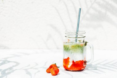 Çilekli kirazlı latte Parlak güneşin altında ve eğreltiotunun gölgesinde