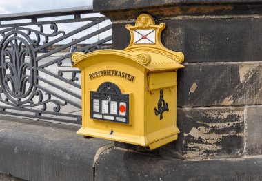 Klasik dekoratif sarı posta kutusu Dresden 'in resimli eski kasabasındaki tarihi kumtaşı balyasına iliştirilmiş..