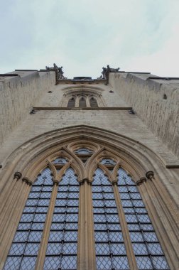 View of english gothic building facade and sky of University Church of St Mary the Virgin Tower with ogival arched windows and intricate architectural detailing from Oxford High Street, Oxford, United Kingdom.